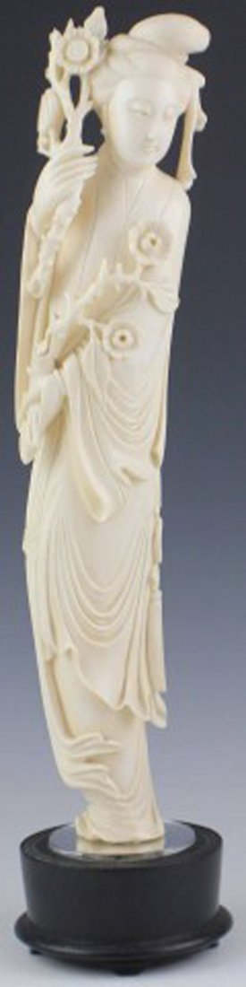 LARGE CARVED IVORY FIGURINE OF QUAN YIN: LARGE CARVED IVORY FIGURINE OF QUAN YIN Large finely carved Ivory figure featuring Quan Yin holding a branch of flowers in each hand. Long flowing robes with detailed folds and a tassel belt are inclu
