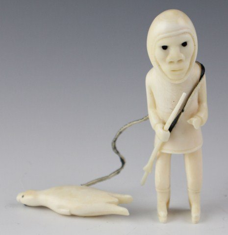 GREENLAND INUIT TUPILAK CARVED IVORY HUNTER FIGURE: NATIVE GREENLAND ESKIMO INUIT TUPILAK CARVED IVORY HUNTER FIGURE Features hunter with spear dragging seal. Carved from whale's tooth. , Size: 4.5", Est. 300-600, Lot 30391
