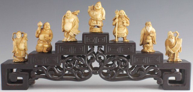 SEVEN LUCKY GODS OF JAPAN IN IVORY: SEVEN LUCKY GODS OF JAPAN IN IVORY All 7 of the Japanese Lucky Gods hand carved in ivory. Set comes with a specialty made carved rosewood base. , Size: 2" Figures and 3.5" Base., Est. 300-500, Lot 304