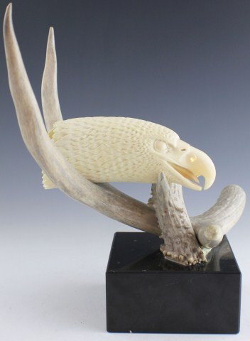 CARVED EAGLE HEAD SPERM WHALE TOOTH ON ANTLER STAND: CARVED EAGLE HEAD SPERM WHALE TOOTH ON ANTLER STAND Hand carved Sperm Whale tooth in exquisite detail, the form of an eagle's head. The worked tooth sits upon a cleanly polished antler base. Both eagl