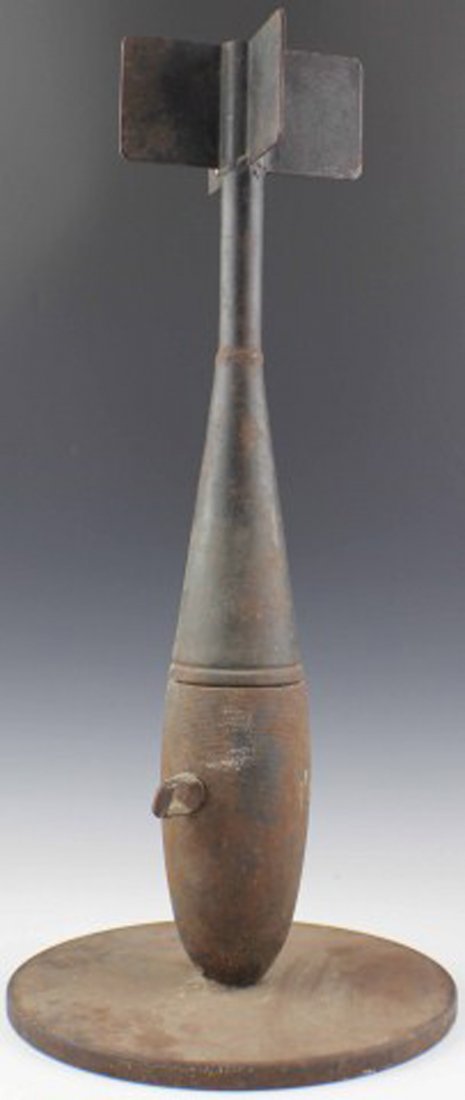 CAST IRON TRENCH ART BOMB: CAST IRON TRENCH ART BOMB Large trench art piece formed of a bomb set onto a disc base nose down. , Size: 25 1/2" tall including 1/2" base, Est. 50-100, Lot 30758