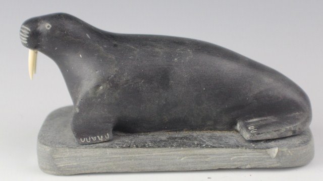 INUIT SOAPSTONE CARVING OF WALRUS WITH IVORY TUSKS: INUIT SOAPSTONE CARVING OF WALRUS WITH IVORY TUSKS Primitive carving of walrus made from soapstone, featuring tusks made of ivory. Size: 5 x 3.5 x 2" (with base), Est. 50-100, Lot: 32147