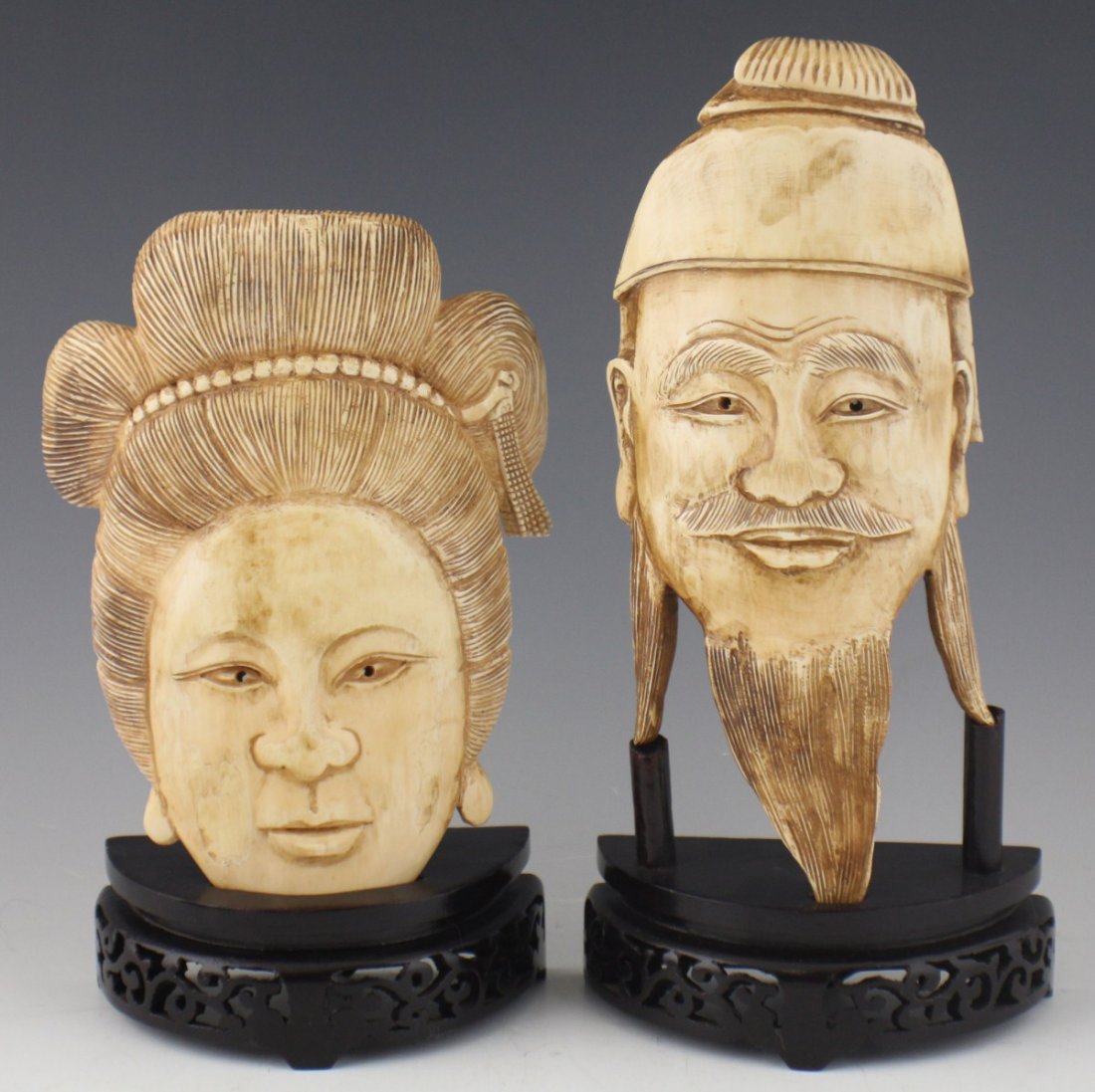 JAPANESE PAIR OF MALE & FEMALE IVORY CARVED FACES: JAPANESE PAIR OF MALE & FEMALE IVORY CARVED FACES Japanese pair of male and female carved ivory faces. Woman has hair of in bun, and man has long beard. Both rest on wooden stands. Size: 7.5", 9" Est.