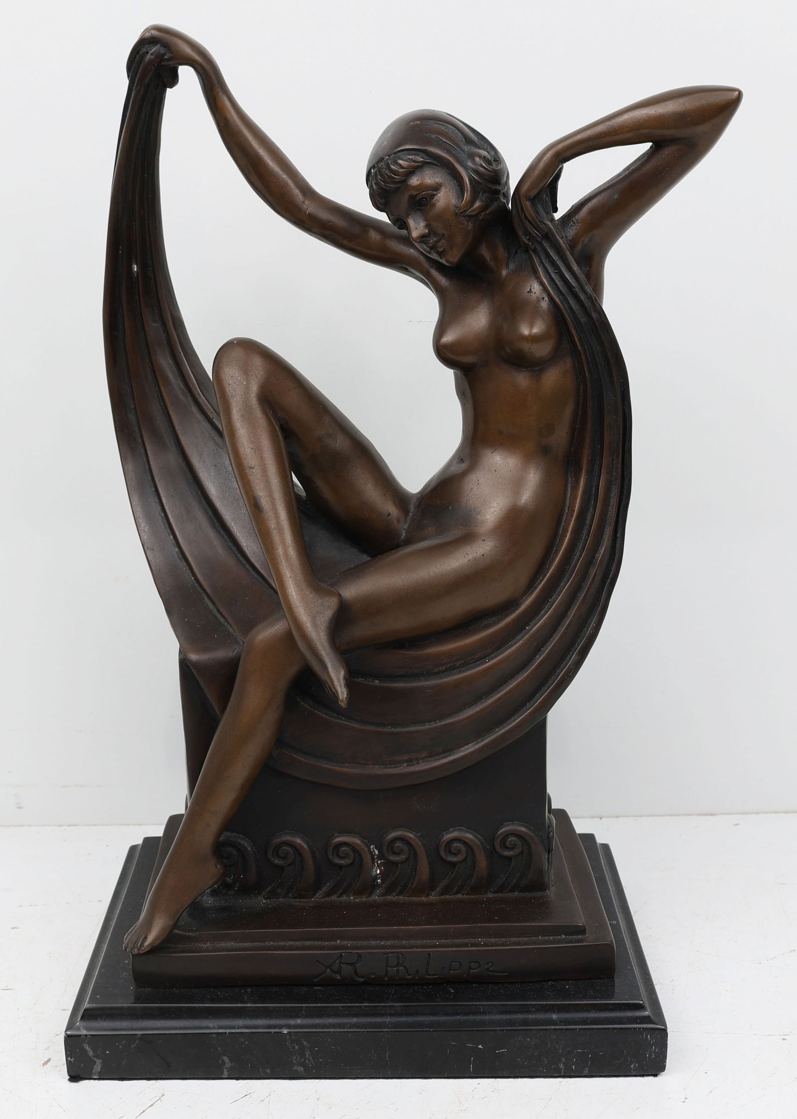 ART DECO BRONZE RECLINING WOMAN XR PHILIPPE: A captivating Art Deco bronze sculpture: A reclining nude woman, her form gracefully draped in fabric, rests upon a bench. The faux marble base supports her, while cresting waves evoke movement and se