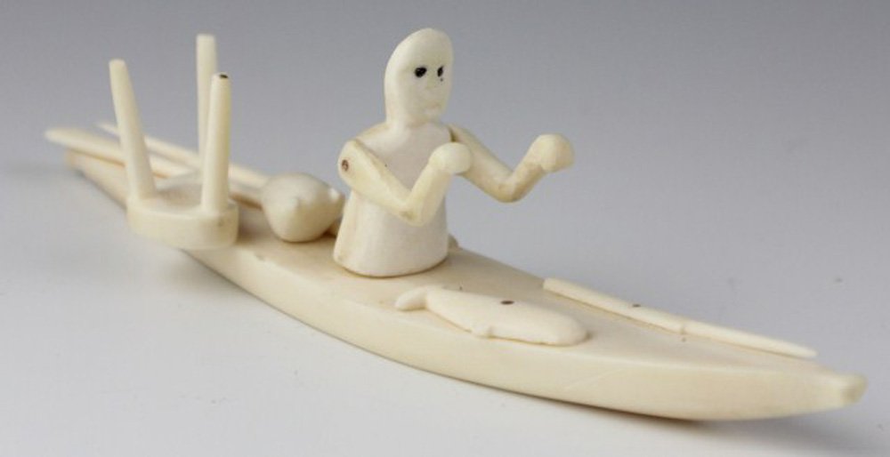 GREENLAND INUIT CARVED IVORY KAYAKER: GREENLAND INUIT CARVED IVORY KAYAKER A native Inuit Kayak with gear and boater carved from whale's tooth. Size: 6" Est. $100-200 Lot: 33083