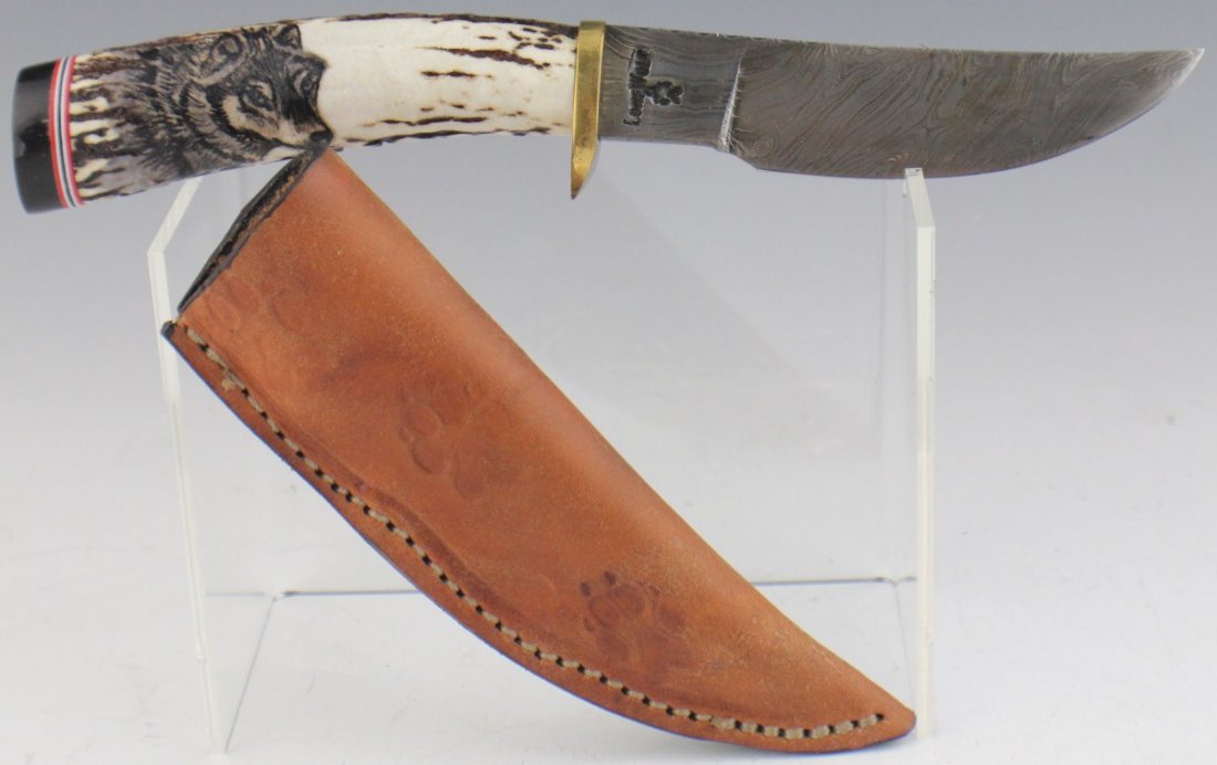 LONE WOLF HAND MADE 4" BLADE CUSTOM KNIFE: LONE WOLF HAND MADE 4" BLADE CUSTOM KNIFE Single edged custom damascus steel knife. Made by Lone wolf. Brass metal cross guard with stag handle. The handle has a scrimshaw type wolf picture. Blade is 