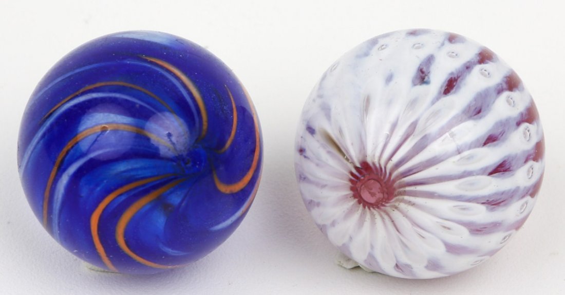 LOT OF TWO SIGNED GLASS JIM DAVIS MARBLES: LOT OF TWO SIGNED GLASS JIM DAVIS MARBLES Jim Davis signed marbles 1. Blue and orange swirl 38.5mm 2. Red with white lighting 40.5mm. Est. $30-60 Lot: 33308