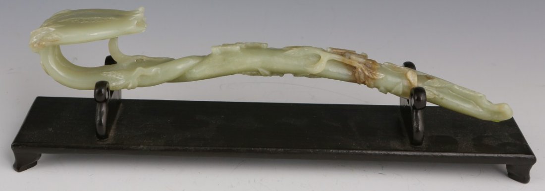 FINE CHINESE CELADON JADE RUYI SCEPTER: FINE CHINESE CELADON JADE RUYI SCEPTER A finely carved celadon green jade Ruyi scepter, brown veins to the lower third. Carved in flower form. Mounted to a later wood stand. Size: 12"