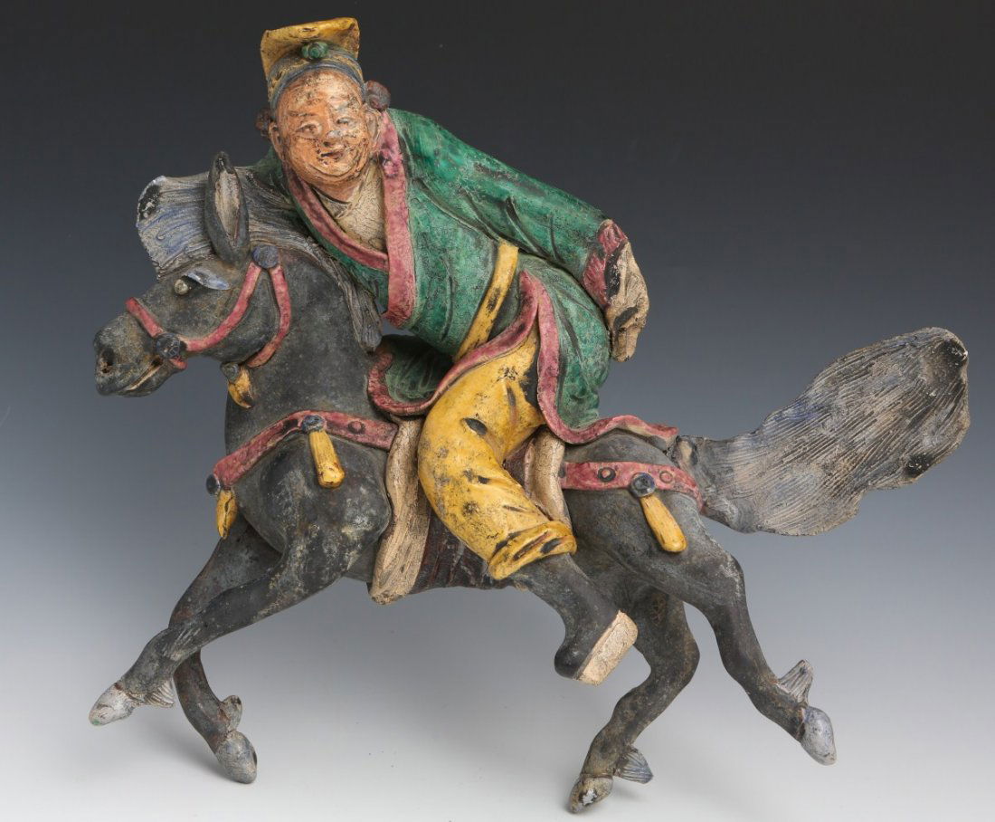 CHINESE ROOF TILE HORSE AND MAN FIGURE: CHINESE ROOF TILE HORSE AND MAN FIGURE A Chinese roof tile figure formed as a man riding a galloping horse. Varying painted colors on ceramic base over which a glaze has been applied. Crazing and age