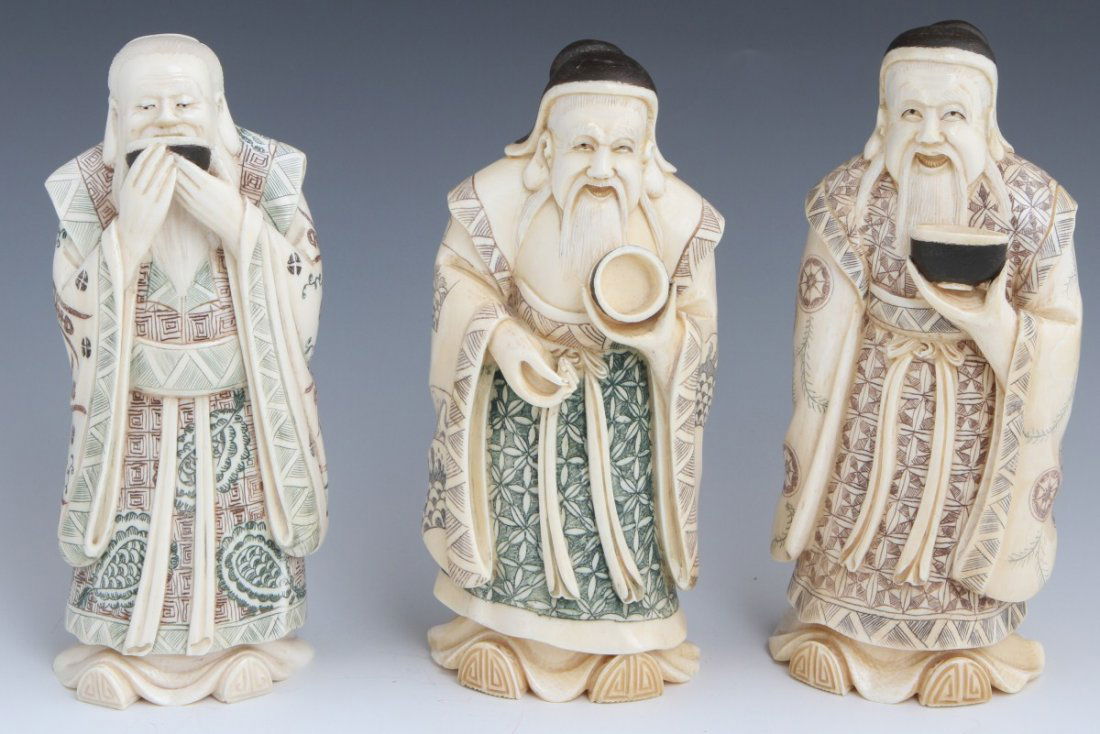 THREE CARVED IVORY JAPANESE OKIMONO: THREE CARVED IVORY JAPANESE OKIMONO A group of very elegantly carved and scrimmed Japanese Okimono sage figures. The three wise men carry a bowl each and are clothed in flowing robes that cover all bu