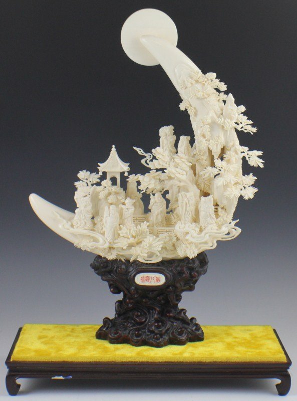 A FINE CHINESE CARVED IVORY DIORAMA 8 IMMORTALS: A FINE CHINESE CARVED IVORY DIORAMA 8 IMMORTALS A very ornate village scene showing the eight immortals. The scene incorporates two crescent tusks and is presented on a rosewood stand. Size: 21" tall