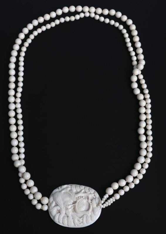 CHINESE CARVED IVORY DOUBLE STRAND NECKLACE: CHINESE CARVED IVORY DOUBLE STRAND NECKLACE Chinese carved ivory bead necklace with 2.5 X 2.25" pendant attached in center. Pendant has crane and tree motif. Smaller beads measure 7mm and larger beads