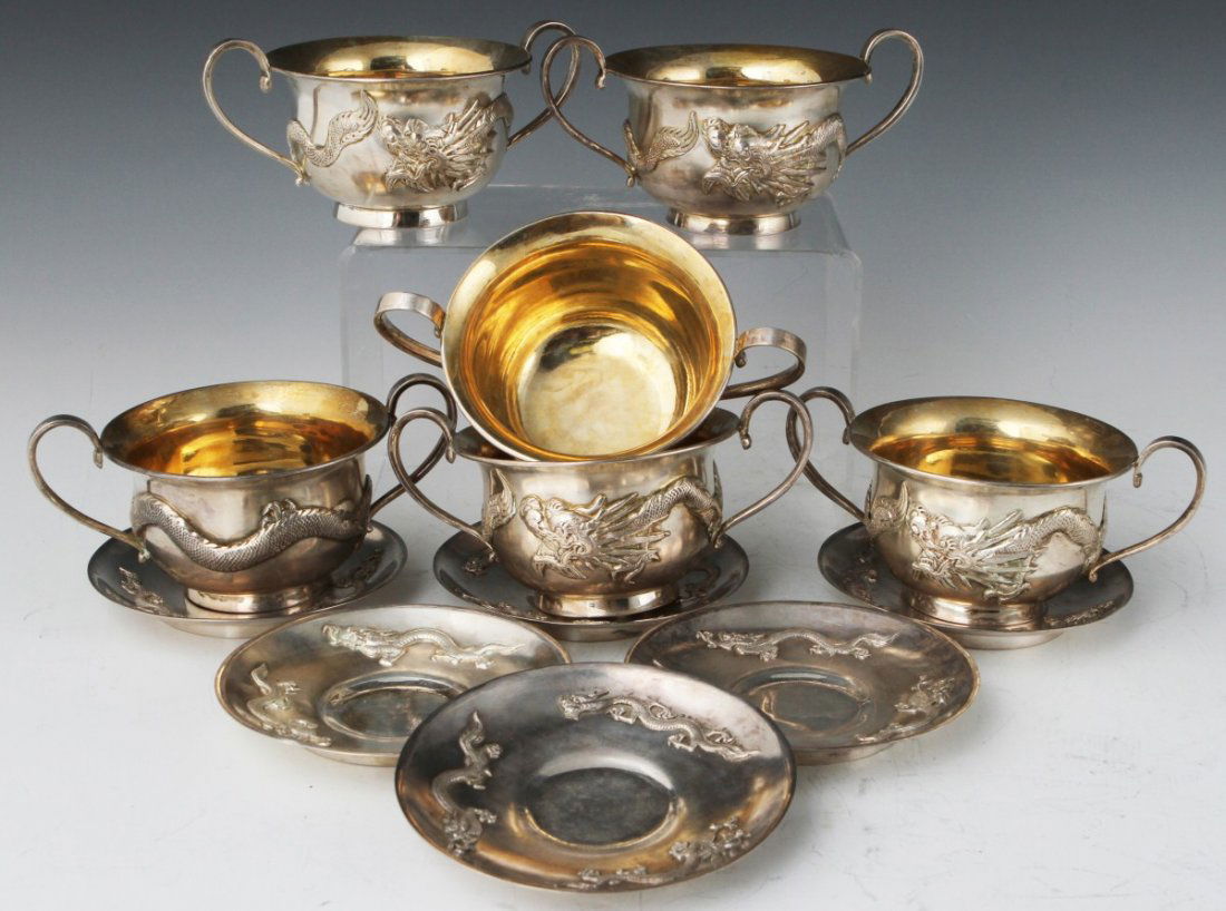 CHINESE SILVER GILT TEA CUP AND SAUCER SET: CHINESE SILVER GILT TEA CUP AND SAUCER SET A set of Chinese saucers and Hong Kong tea cups, both 90 percent silver and have applied dragon designs. Saucers are exported by Luen Hing, marked "90 LH." C