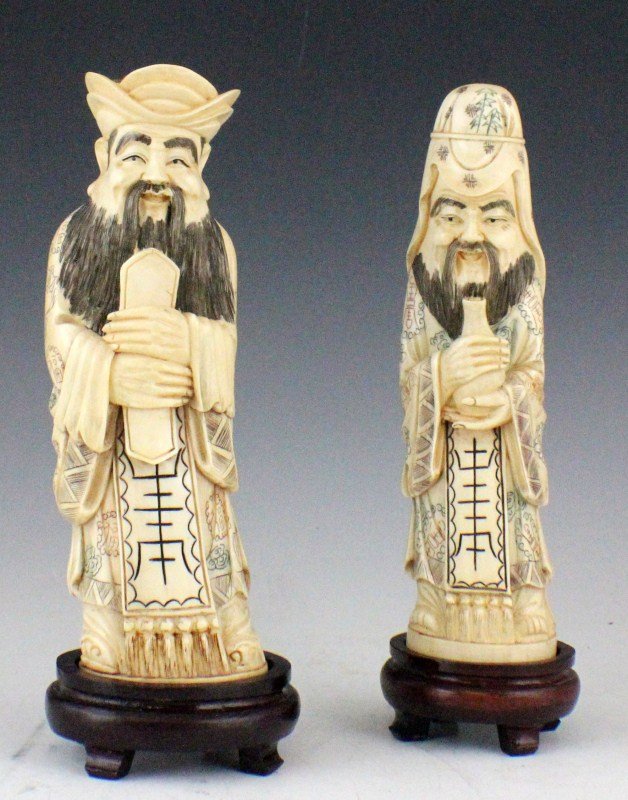 TWO ASIAN IVORY POLYCHROME DEITY FIGURES: TWO ASIAN IVORY POLYCHROME DEITY FIGURES Two ivory deity figures, wearing robes decorated with bats. Both figures are signed on the bottom. Size: 8"