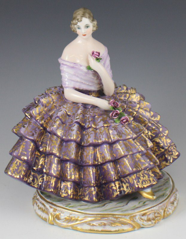 EARLY 20TH CEN. GUIDO CACCIAPUOTI PORCELAIN FIGURE: EARLY 20TH CEN. GUIDO CACCIAPUOTI PORCELAIN FIGURE Guido Cacciapuoti (Italian, 1892-1953). Early 20th century Italian porcelain figurine. Features seated girl in purple dress with gilt accents holding