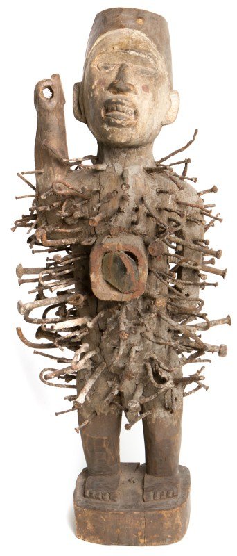 WOODEN AFRICAN NSIKI NKONDI NAIL FETISH: WOODEN AFRICAN NSIKI NKONDI NAIL FETISH An African nsiki nkondi nail fetish carved from wood. Bilongo in the belly is covered with a piece of glass. Center of wood features cracking. Spear is missing 