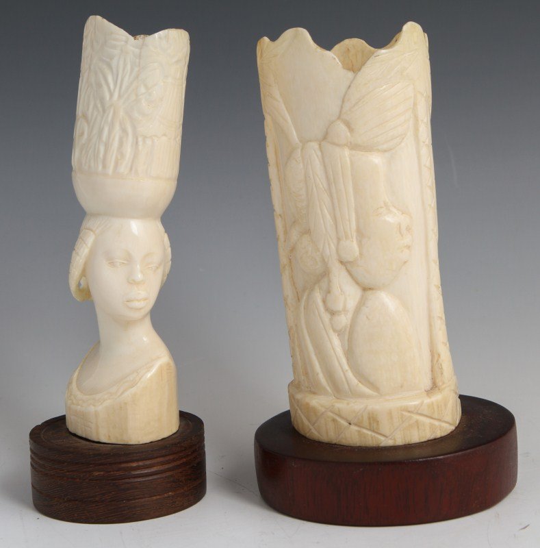 TWO AFRICAN CARVED FEMALE IVORY BUSTS: TWO AFRICAN CARVED FEMALE IVORY BUSTS Two African Ivory tusks mounted to wooden bases, carved to represent the bust of a female facing to her left. One tusk is carved in relief to the surface, the oth
