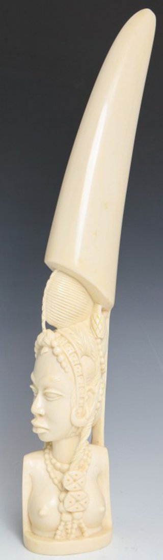 CARVED AFRICAN IVORY TUSK TRIBAL FEMALE BUST: CARVED AFRICAN IVORY TUSK TRIBAL FEMALE BUST Carved African ivory tusk. Topless female bust, hair is braided with tribal ornamentation. The end of the tusk is unworked. High polish, nice even color. S