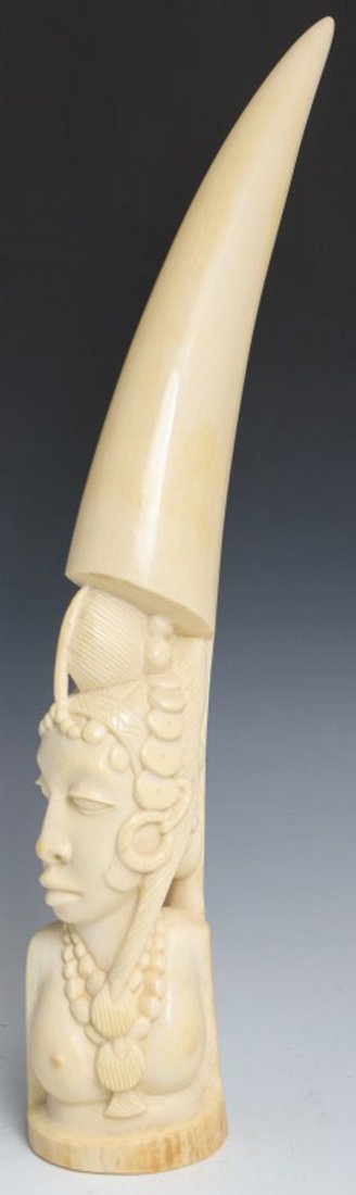 CARVED AFRICAN IVORY TUSK TRIBAL FEMALE BUST: CARVED AFRICAN IVORY TUSK TRIBAL FEMALE BUST Carved African ivory tusk. Topless female bust, hair is braided with tribal ornamentation. The end of the tusk is unworked. High polish, nice even color. S
