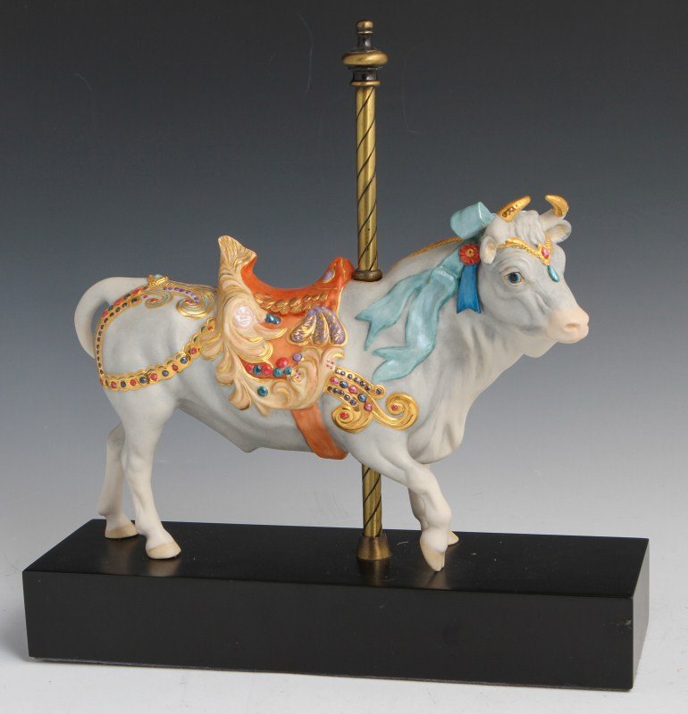 CYBIS PORCELAIN CAROUSEL BULL #132: CYBIS PORCELAIN CAROUSEL BULL #132 Porcelain carousel bull figurine by Cybis, with blue bow detail and ornate saddle with ladies' faces added into the design. Size: 12" by 12"