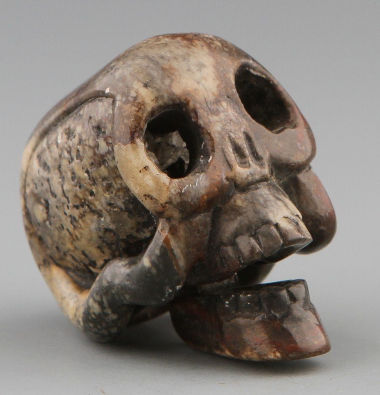JAPANESE CARVED STONE NETSUKE SKULL: JAPANESE CARVED STONE NETSUKE SKULL Japanese carved stone karakuri-netsuke of a skull with moving jaw. Size: 1.5 x 1.5 x 1" Weight: 41g