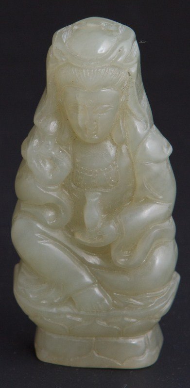 CHINESE CARVED JADE PENDANT OF SEATED GUANYIN: CHINESE CARVED JADE PENDANT OF SEATED GUANYIN Small light green jade pendant of Guanyin holding the bottle of compassion. Seated on a lotus throne. Size: 3"