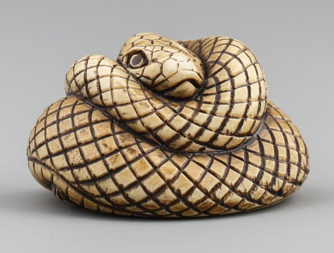 JAPANESE CARVED IVORY NETSUKE COILED SNAKE: JAPANESE CARVED IVORY NETSUKE COILED SNAKE Japanese carved ivory netsuke figure of a coiled snake. Monochrome, highly detailed. Signed. Size: 1.5 x 1.25 x 1" Weight: 24g