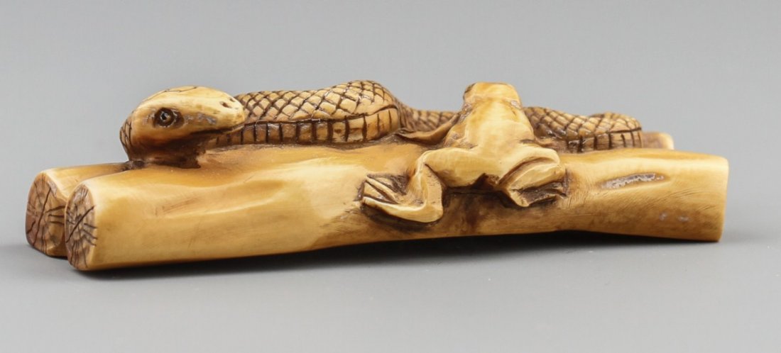 JAPANESE CARVED IVORY NETSUKE SNAKE & FROG: JAPANESE CARVED IVORY NETSUKE SNAKE & FROG Japanese carved ivory netsuke figure of a frog and a snake on logs. Signed. Size: 2.25 x .75 x .5" Weight: 16g