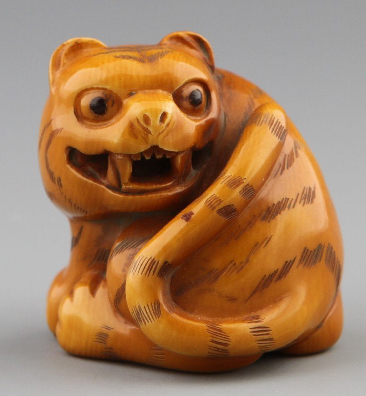 JAPANESE CARVED IVORY NETSUKE TIGER: JAPANESE CARVED IVORY NETSUKE TIGER Japanese carved ivory netsuke of tiger with even patina and monochromed details, Signed Tomomitsu. Size: 1.5 x 1.5 x 1.25" Weight: 55g