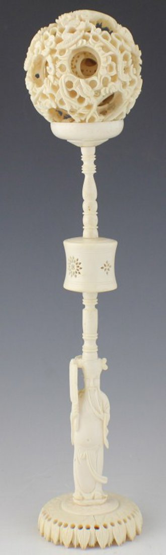 CHINESE CARVED IVORY PUZZLE BALL WITH STAND: CHINESE CARVED IVORY PUZZLE BALL WITH STAND 2.75" diameter Chinese carved ivory puzzle ball with 12 layers sitting atop carved ivory stand featuring monk with fan. Small chip and old repair to base. F
