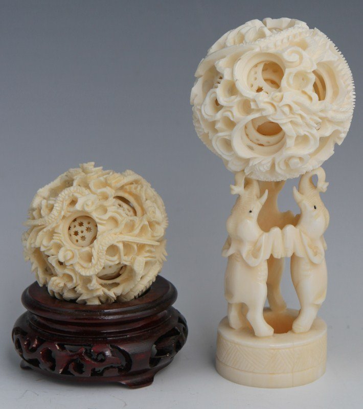 2 CHINESE CARVED IVORY PUZZLE BALLS: 2 CHINESE CARVED IVORY PUZZLE BALLS Lot of 2 carved ivory Chinese puzzle balls. 2" ball is supported by 3 carved ivory standing elephants. The smaller, slightly darker puzzle ball rests on a rosewood 