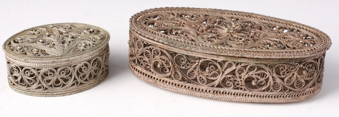 (2) SILVER FILIGREE DRESSER BOXES: (2) SILVER FILIGREE DRESSER BOXES A pair of oval dresser top boxes of silver filigree construction. Intricate waves, coils and ropes of silver constitute their form. Either pill or ring boxes with det