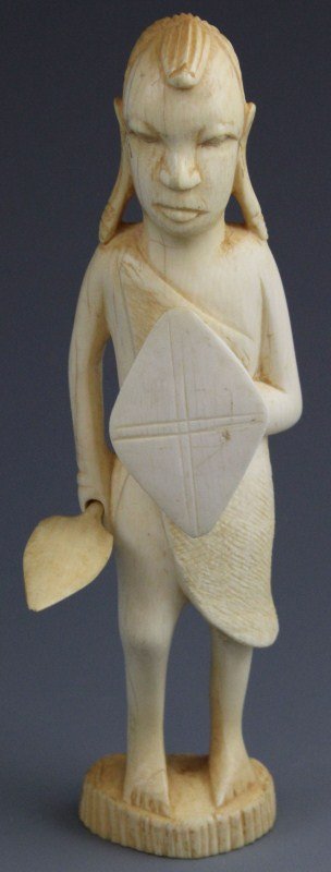 CARVED IVORY STATUE OF AN ARMED AFRICAN WARRIOR: CARVED IVORY STATUE OF AN ARMED AFRICAN WARRIOR Carved ivory of an African warrior holding a spear and shield. 167.1g 7"