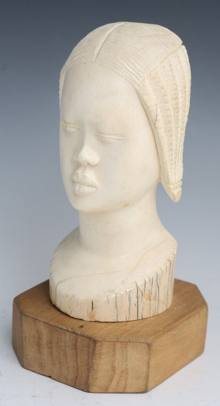 AFRICAN CARVED IVORY FEMALE BUST WITH BRAIDS: AFRICAN CARVED IVORY FEMALE BUST WITH BRAIDS African carved ivory figural bust of female figure with braids, 20th century. Attached to wooden base. Some cracking in hair and around base. Size: 7.5" We