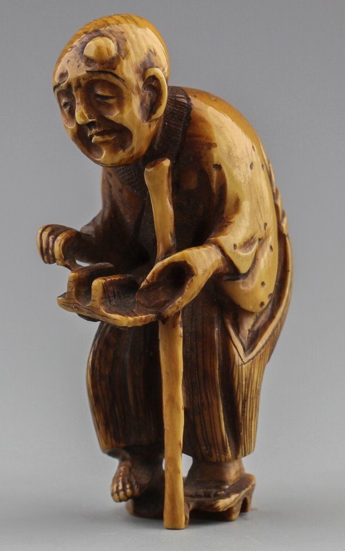 JAPANESE CARVED IVORY NETSUKE MAN WITH SHOE