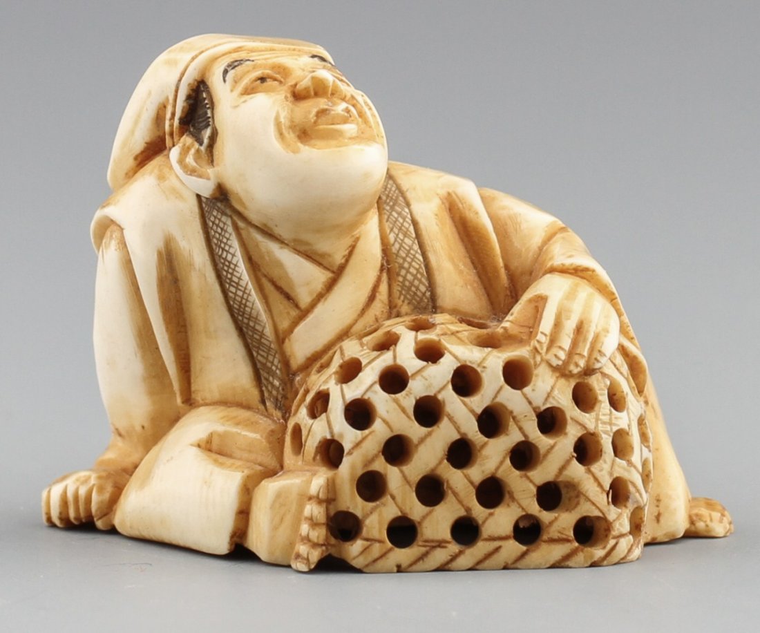 JAPANESE CARVED IVORY NETSUKE SEATED MAN W/ BASKET: JAPANESE CARVED IVORY NETSUKE SEATED MAN W/ BASKET Japanese carved ivory netsuke figure of seated man with basket. Signed on the bottom. Size: 1.75 x 1.5 x 1.25" Weight: 19.8g