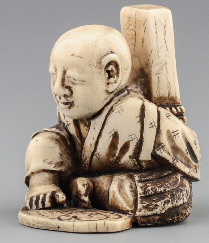 JAPANESE CARVED IVORY NETSUKE PRISONER BOUND: JAPANESE CARVED IVORY NETSUKE PRISONER BOUND Carved ivory netsuke of a seated prisoner bound by rope to a wooden stake. Small mouse is etched into base by prisoner's feet. Very detailed etching and st