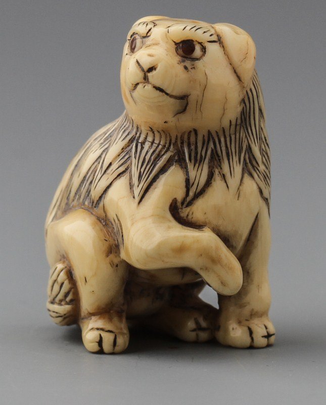 JAPANESE CARVED IVORY NETSUKE FOO DOG: JAPANESE CARVED IVORY NETSUKE FOO DOG Japanese carved ivory netsuke of a foo dog in the sitting position. Signed on leg. Size: 1.5 x 1.25" Weight: 18g