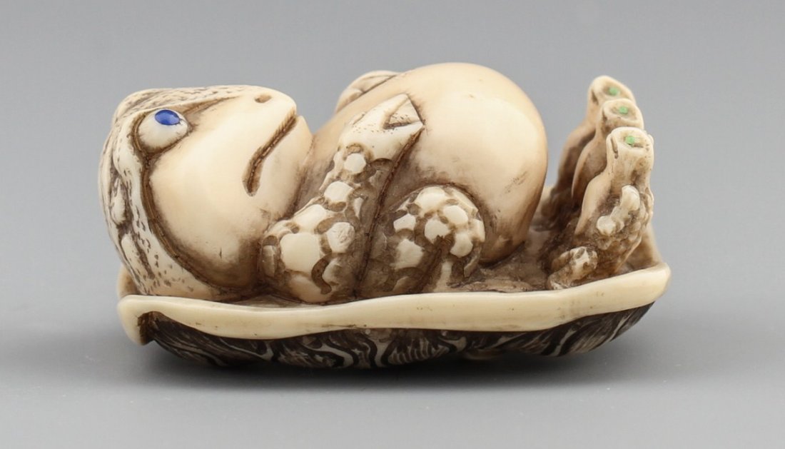 JAPANESE CARVED IVORY NETSUKE MOM FROG AND KIDS: JAPANESE CARVED IVORY NETSUKE MOM FROG AND KIDS Japanese carved ivory netsuke of mother frog and three smaller frogs lying on a mushroom top. signed Tomoichi. Size: 1 x 1.75" Weight: 25g