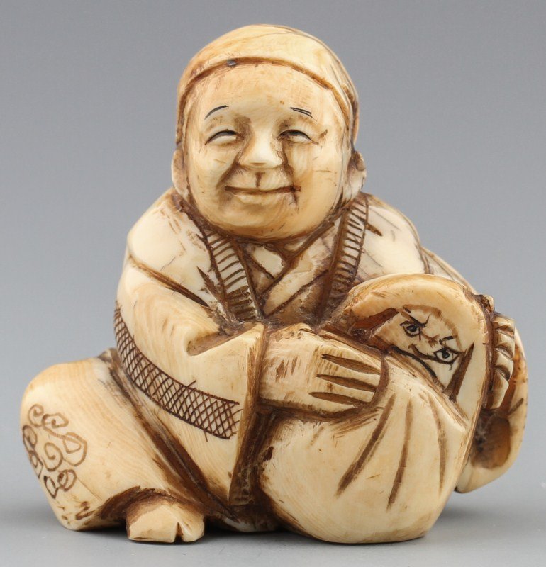 JAPANESE CARVED IVORY NETSUKE MAN WITH DARUMA