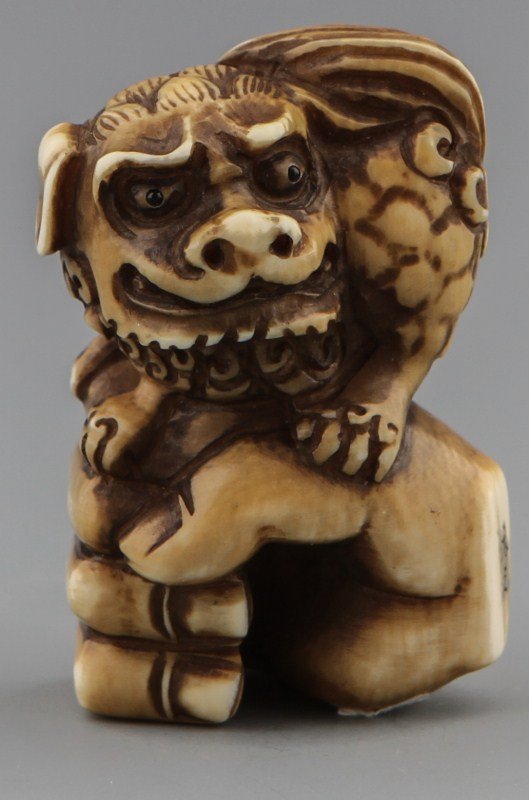 JAPANESE CARVED IVORY NETSUKE SHISHI HIROYUKI: JAPANESE CARVED IVORY NETSUKE SHISHI HIROYUKI Japanese carved ivory netsuke figure of fist with foo dog. Signed, Hiroyuki. Stained. Size: 2 x 1.25 x .75" Weight: 31.6g