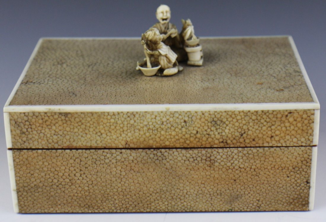 SHAGREEN AND IVORY FIGURAL CIGARETTE BOX: SHAGREEN AND IVORY FIGURAL CIGARETTE BOX Shagreen and ivory over a wood construction cigarette box. Shagreen covers five surfaces bordered with ivory trim, and a very detailed ivory Okimono group is a