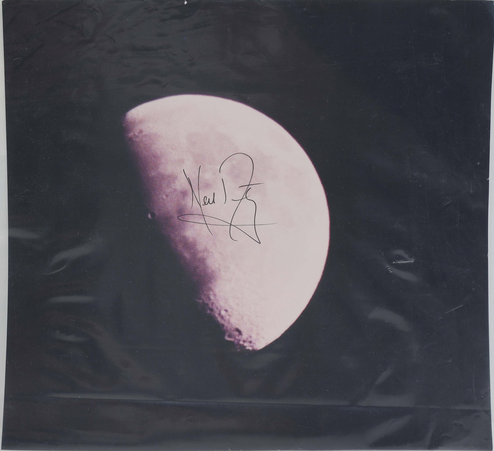 NEIL ARMSTRONG SIGNED VINTAGE LUNAR PHOTOGRAPH: A striking signed photograph by Neil Armstrong, featuring a crisp lunar phase with his bold signature centered across the image. The composition pairs the Moon's timeless, cratered surface with the au