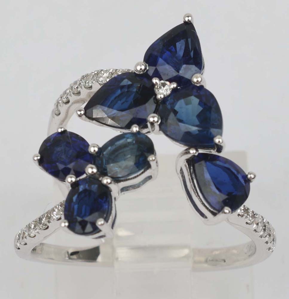 18K WHITE GOLD SAPPHIRE DIAMOND RING FLORAL MOTIF: 18K White Gold Ring Featuring Sapphires and Diamonds in a floral motif. Seven sapphires totaling 3.51 ct and twenty accent round diamonds .20 ct. Size: 6 adjustable Weight: 4.2 G Must be paid by Certi