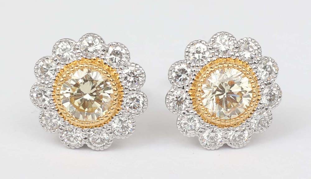 18K WHITE & LIGHT FANCY YELLOW DIAMOND EARRINGS: 18K 750 white with yellow gold accent. Solitaire center is Light Fancy Yellow 1.20 carat old European cut SI2 & surrounding is White Diamond 0.65 carat (22) round brilliant cut F-G VS1-VS2 Halo Style 