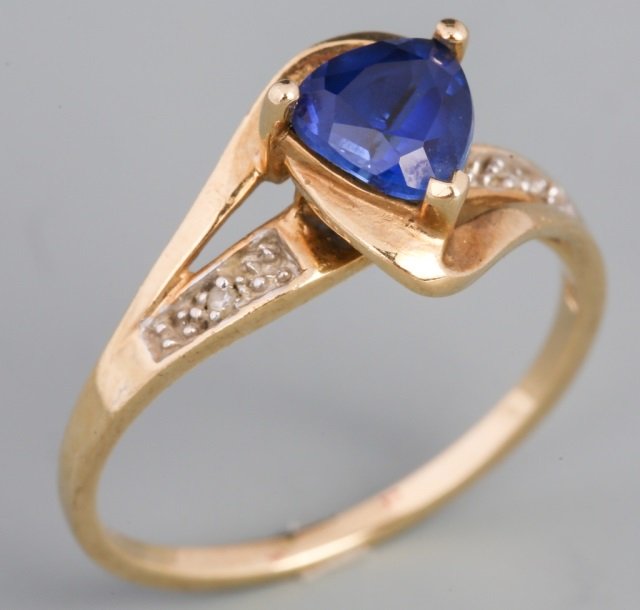 TANZANITE AND DIAMOND RING: TANZANITE AND DIAMOND RING One central .95ct trilliant cut Tanzanite accompanied by one small accent diamond on each side of the tanzanite. Produced in 10k yellow gold. Weight: 2.2 g Size: 6.75