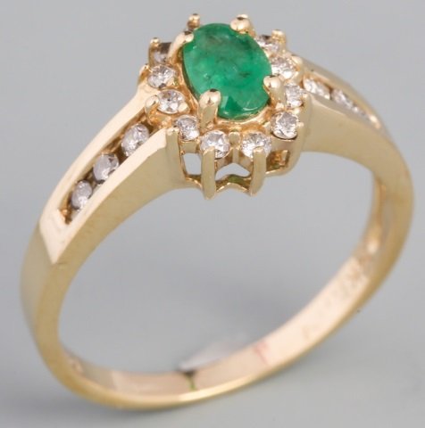 14K YELLOW GOLD OVAL CUT EMERALD AND DIAMOND RING: 14K YELLOW GOLD OVAL CUT EMERALD AND DIAMOND RING Oval cut emerald, measuring 6mm by 4mm, surrounded by eighteen accent diamonds in a 14K yellow gold fashion ring setting. Weight: 2.9 g Size: 7.5