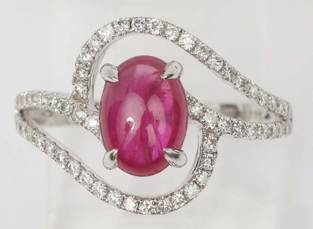 18K WHITE GOLD RUBY & DIAMOND RING: 18k white gold cabochon ruby with diamond swirl motif ring. Gemstones: Ruby & Diamond 60 round diamonds .37 ct.One round exceptional quality ruby cabochon 1.50 ct. 18K white gold Size: 6.25 Weight: 2.