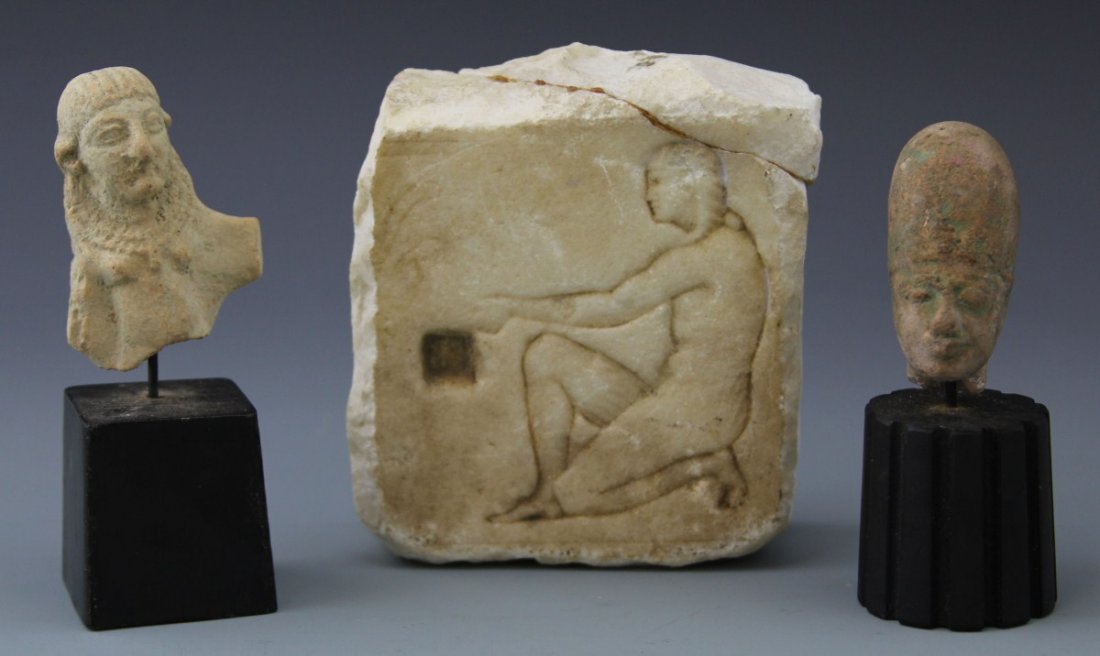 (3) ANCIENT EGYPTIAN AND GRECO ROMAN ARTIFACTS: (3) ANCIENT EGYPTIAN AND GRECO ROMAN ARTIFACTS Lot of three ancient artifacts; Egyptian bust on stand, female figure donning a decoration collar and plaited hair 5"; Egyptian head on stand of male fig