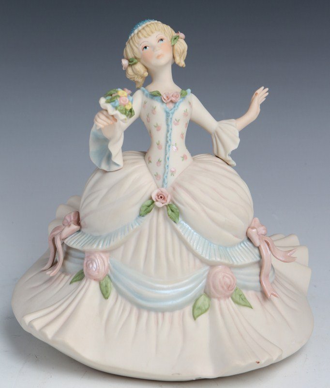 CYBIS PORCELAIN GIRL WITH BOWS & FLOWERS FIGURE: CYBIS PORCELAIN GIRL WITH BOWS & FLOWERS FIGURE A Cybis porcelain figure of a girl holding a bouquet of flowers wearing a ball gown style dress with bows. Stamped at base. Small loss to underside of b